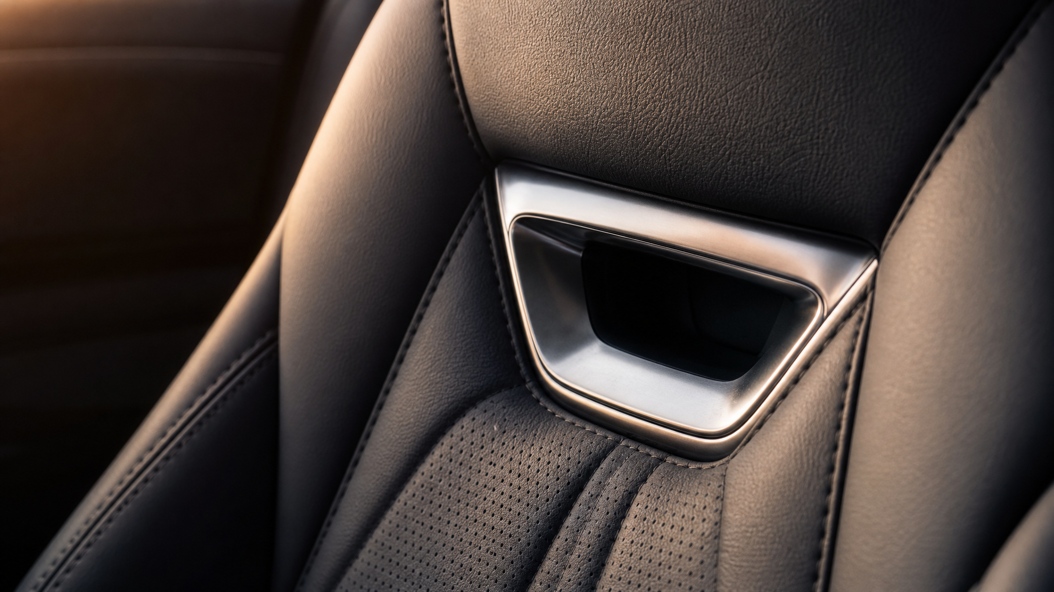 Close-up comparison of soft seat materials meeting a small hard metal insert in a luxury car seat